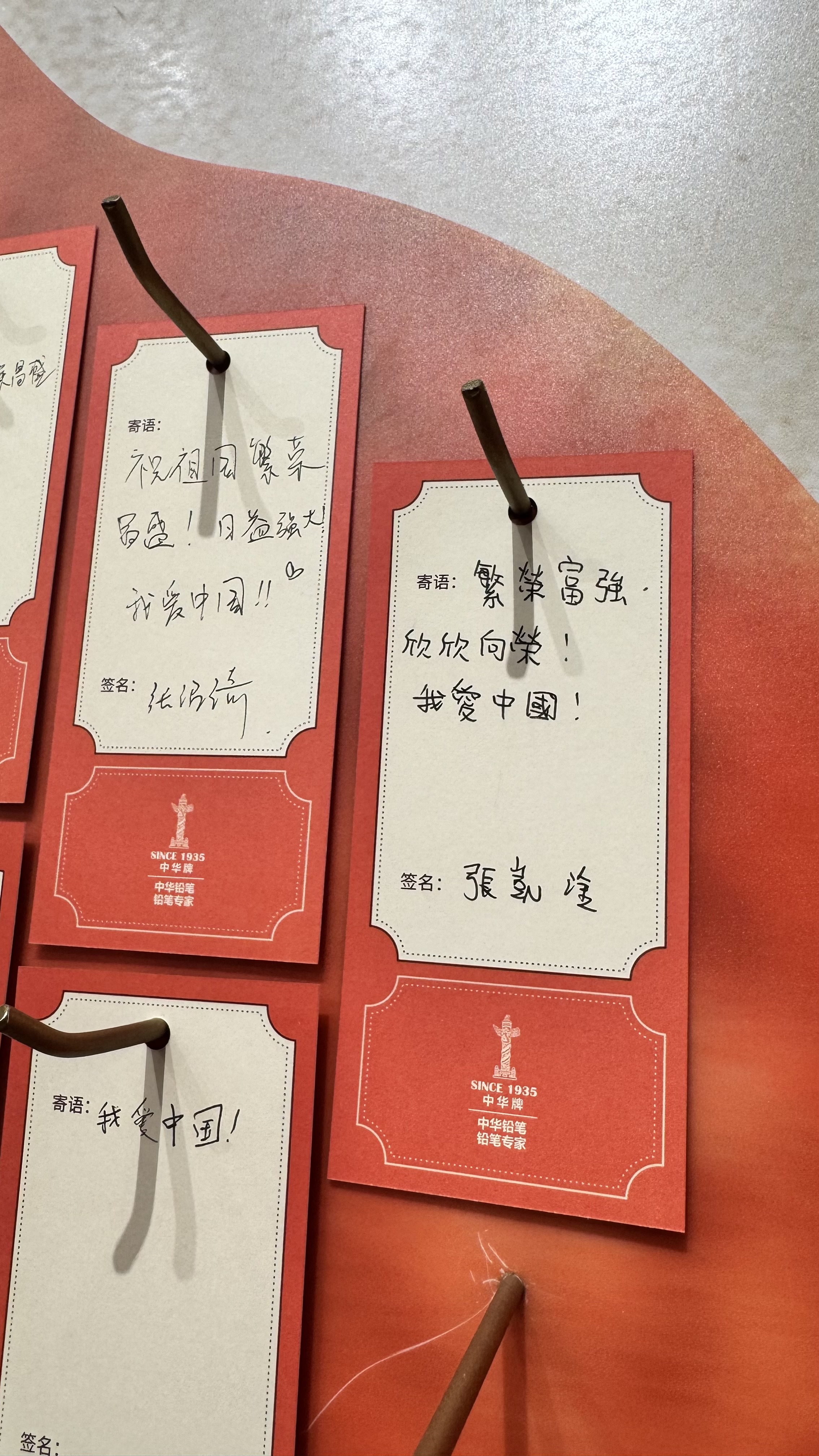 Red and white cards with handwritten Chinese text are displayed on a board, attached with brown strings