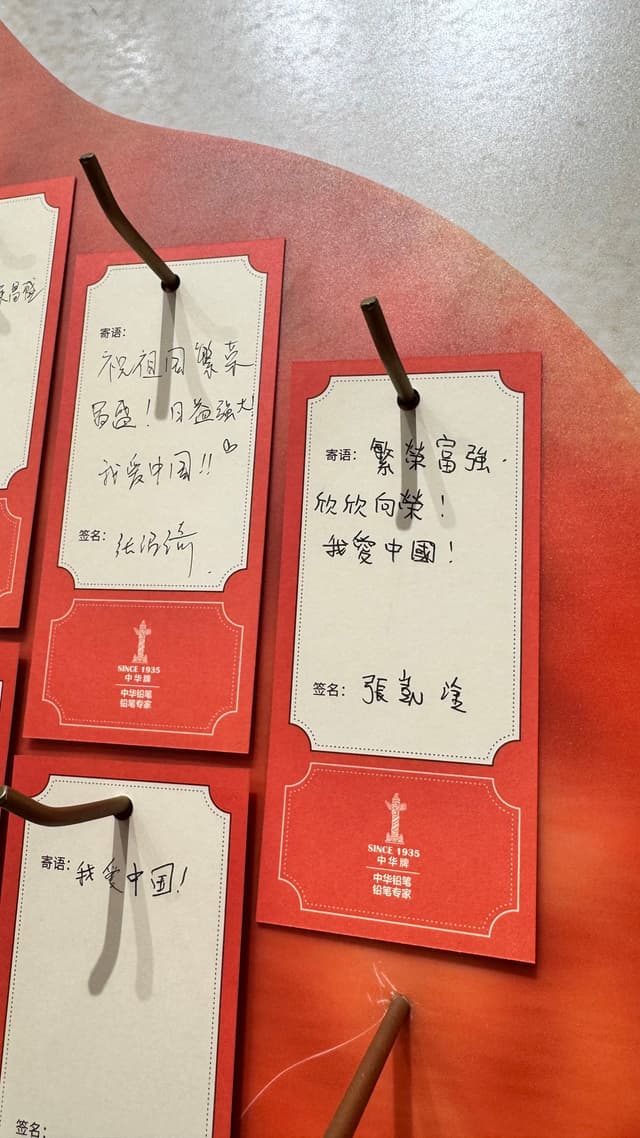 Red and white cards with handwritten Chinese text are displayed on a board, attached with brown strings
